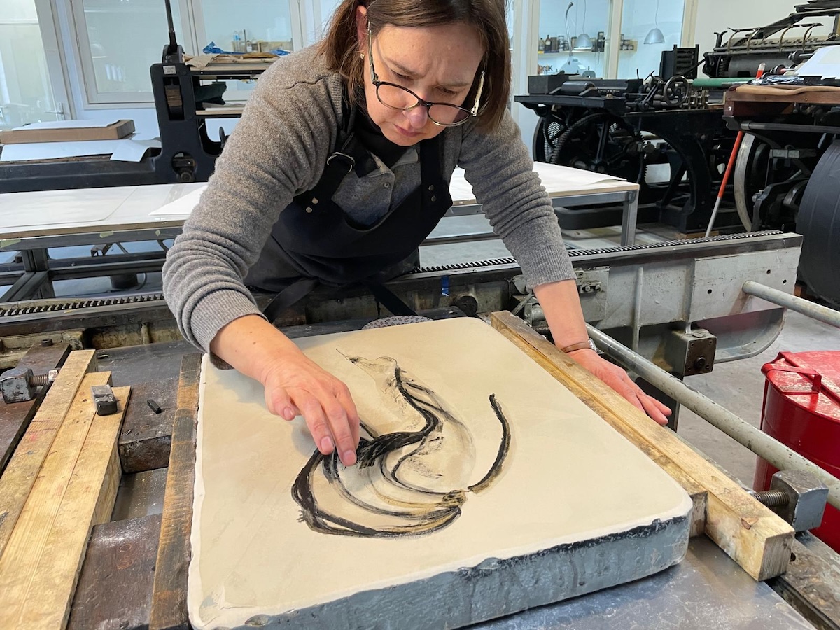Ina van Zyl bewerkt met haar vingers een tekening op een lithosteen