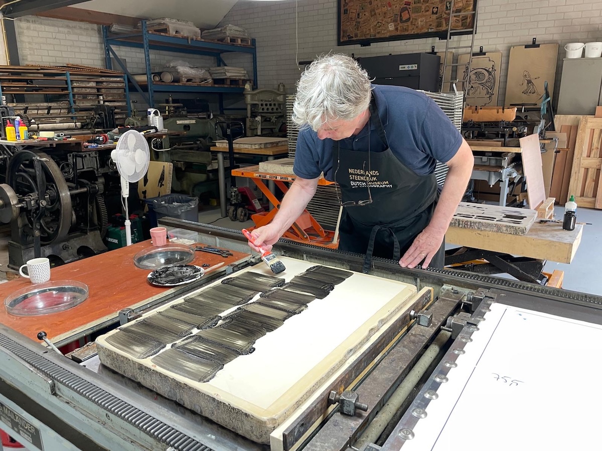 Renée Korten brengt met een kwast inkt aan op een lithografische steen