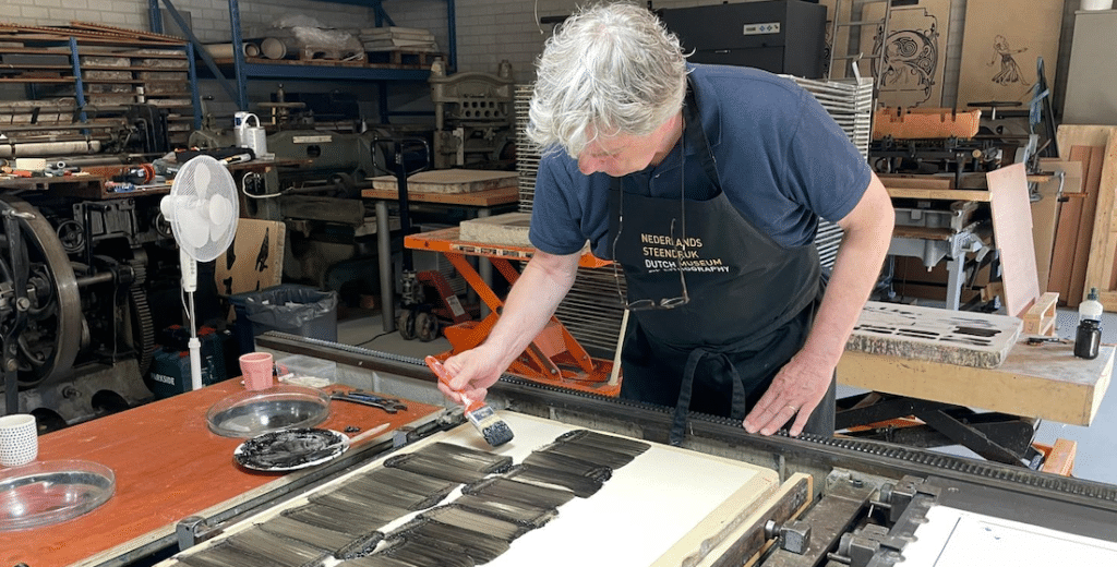 Renée Korten brengt met een kwast inkt aan op een lithografische steen