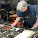Renée Korten brengt met een kwast inkt aan op een lithografische steen